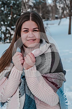 Beautiful young woman in knitted sweater in winter park. Cold weather outdoors. Snow Happy smiling portrait of girl