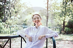 Beautiful young woman laughing and sitting at public park in the morning,Happy and smiling,Relaxing time,Positive thinking