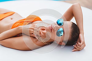 Beautiful young woman laying in bikini during sunbath next to swimming pool