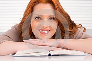 Beautiful young woman leaning on book.