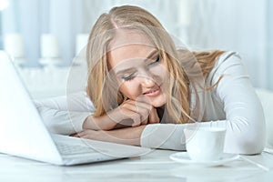 Beautiful young woman leaning on table with laptop