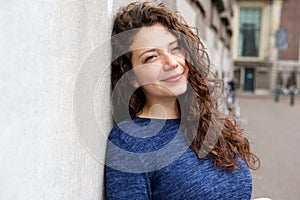 Beautiful young woman leaning to a wall