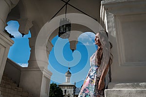 Beautiful young woman in light dress stands at the entrance of the church