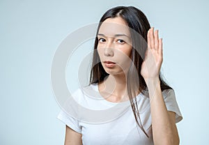 Beautiful young woman listening gossips and holding her hand near the ear