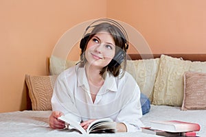 Beautiful young woman listening to audiobook at home. Happy girl wearing headphones listen to calm music in living room