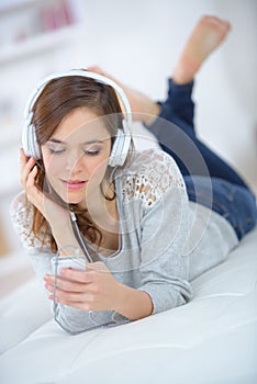 Beautiful young woman listening to music in bed