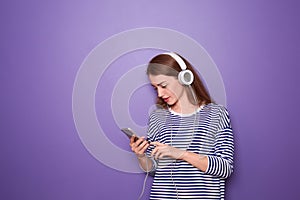 Beautiful young woman listening to music on color background