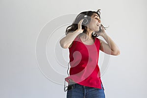 Beautiful young woman listening to music on her mobile phone with headset and having fun over white background. Casual clothing.