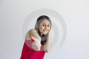 Beautiful young woman listening to music on her mobile phone with headset and having fun over white background. Casual clothing.