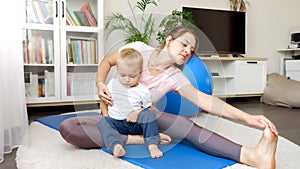 Beautiful young woman with little baby boy sitting on fitness mat and stretching legs. Concept of healthcare, sports and yoga at