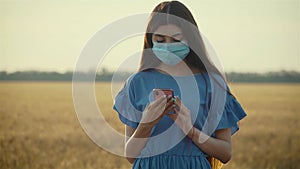 Beautiful young woman with long black hair wearing medical face mask with mobile phone in hands