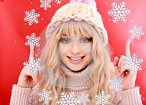 Beautiful young woman with long blond curly hair, dressed in a pink knitted sweater and hat. Beauty, fashion.