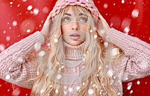 Beautiful young woman with long blond curly hair, dressed in a pink knitted sweater and hat. Beauty, fashion.