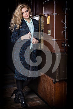 Beautiful young woman with long blond hair, bright make-up Smokey Eyes wearing a sweater next to a dresser and a bar with a c