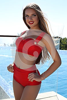 Beautiful young woman with long blond hair in luxurious red swimsuit