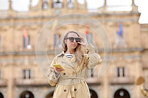 beautiful young woman with long curly hair is wearing sunglasses and using cellphone. girl out and about in the city