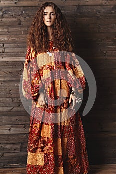 Beautiful young woman with long curly hairstyle, fashion jewelry with brunette hair. Indian style clothes, long dress
