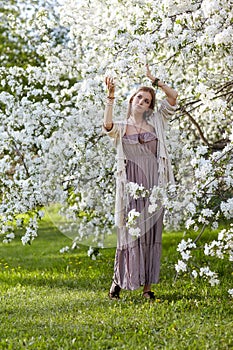 Beautiful young woman in long dress boho style on green grass un