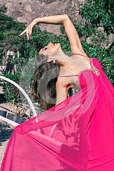 Beautiful young woman in a long evening dress posing in nature, developing it