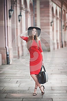 Beautiful young woman with long hair, black hat, shopping bag an