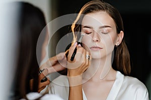 A beautiful young woman with long hair doing makeup for a wedding or photo shoot