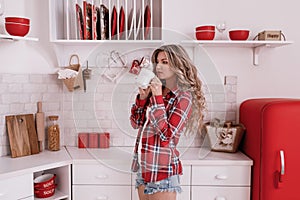 Beautiful Young woman with long hair drinking coffee or tea on the kitchen in the morning. stylish girl in a red shirt in a