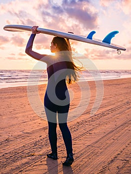Beautiful young woman with long hair. Surf girl with surfboard on a beach at sunset or sunrise. Surfer and ocean