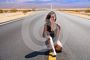 Beautiful young woman with long hair walks along a picturesque empty road in Death Valley overlooking the mountains, USA