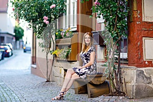 Beautiful young woman with long hairs in summer dress going for a walk in German city. Happy girl enjoying walking in