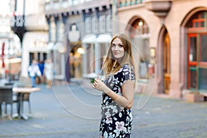 Beautiful young woman with long hairs in summer dress going for a walk in German city. Happy girl enjoying walking in