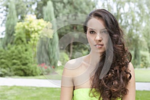 Beautiful young woman with long wavy hair in park