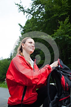 Beautiful young woman looking around and watching nature in natural park/on mountain on a rainy day and taking off