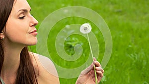 Beautiful Young Woman Looking on Dandelion in her hand