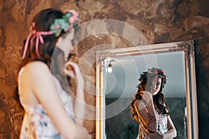 Beautiful young woman looking at her reflection in the mirror