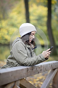 Beautiful young woman looking at her smartphone in the woods