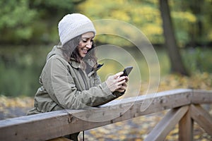 Beautiful young woman looking at her smartphone in the woods