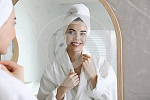 Beautiful young woman looking at herself in bathroom mirror