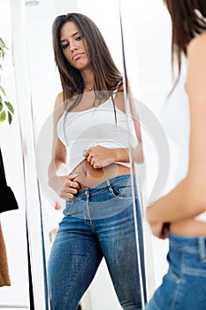 Beautiful young woman looking herself reflection in mirror at home.