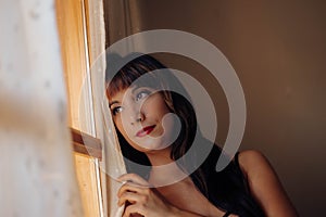 Beautiful young woman looking out the window waiting