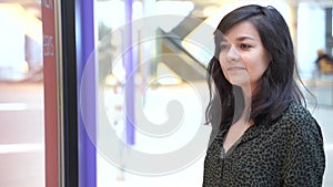 Beautiful young woman looking in a shop window in shopping mall.