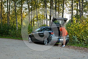 A beautiful young woman looking for a spare wheel in a car boot