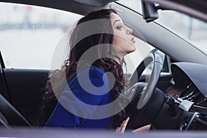 Beautiful young woman looking into the windshield of the car