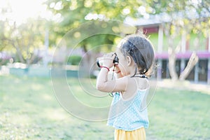 Beautiful young woman looks through binoculars at the national park on a sunny day