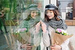 Beautiful, young woman looks at her reflection in the glass and enjoys smiling