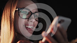 Beautiful young Woman Lying in Bed, Using Smart Phone and Smiling before Sleep. Woman using Cellphone on bed at Night