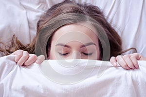 Beautiful young woman lying down in bed and sleeping