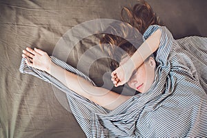 Beautiful young woman lying down in bed and sleeping, top view. Do not get enough sleep concept