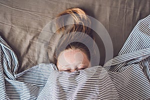 Beautiful young woman lying down in bed and sleeping, top view. Do not get enough sleep concept