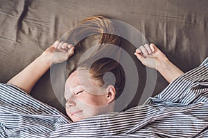 Beautiful young woman lying down in bed and sleeping, top view. Do not get enough sleep concept