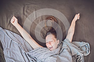 Beautiful young woman lying down in bed and sleeping, top view. Do not get enough sleep concept